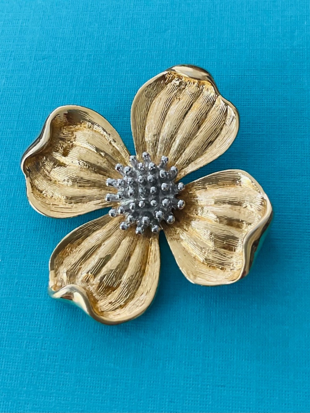 Cosmetic flower pin in golden color, metallic material